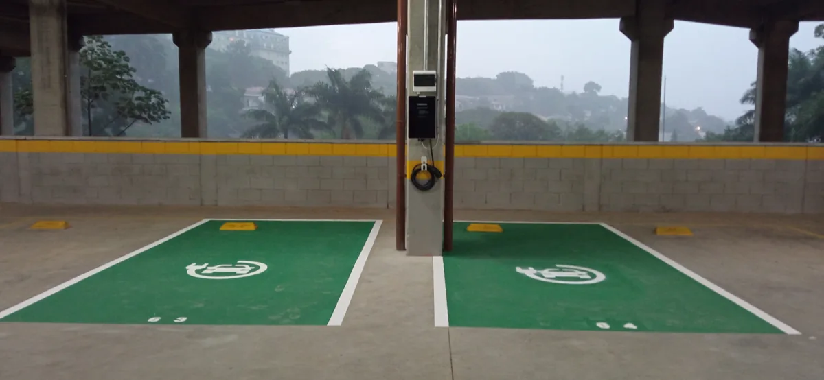Vagas de recarga sinalizadas em verde com carregador de carro elétrico em garagem de condomínio em São Paulo